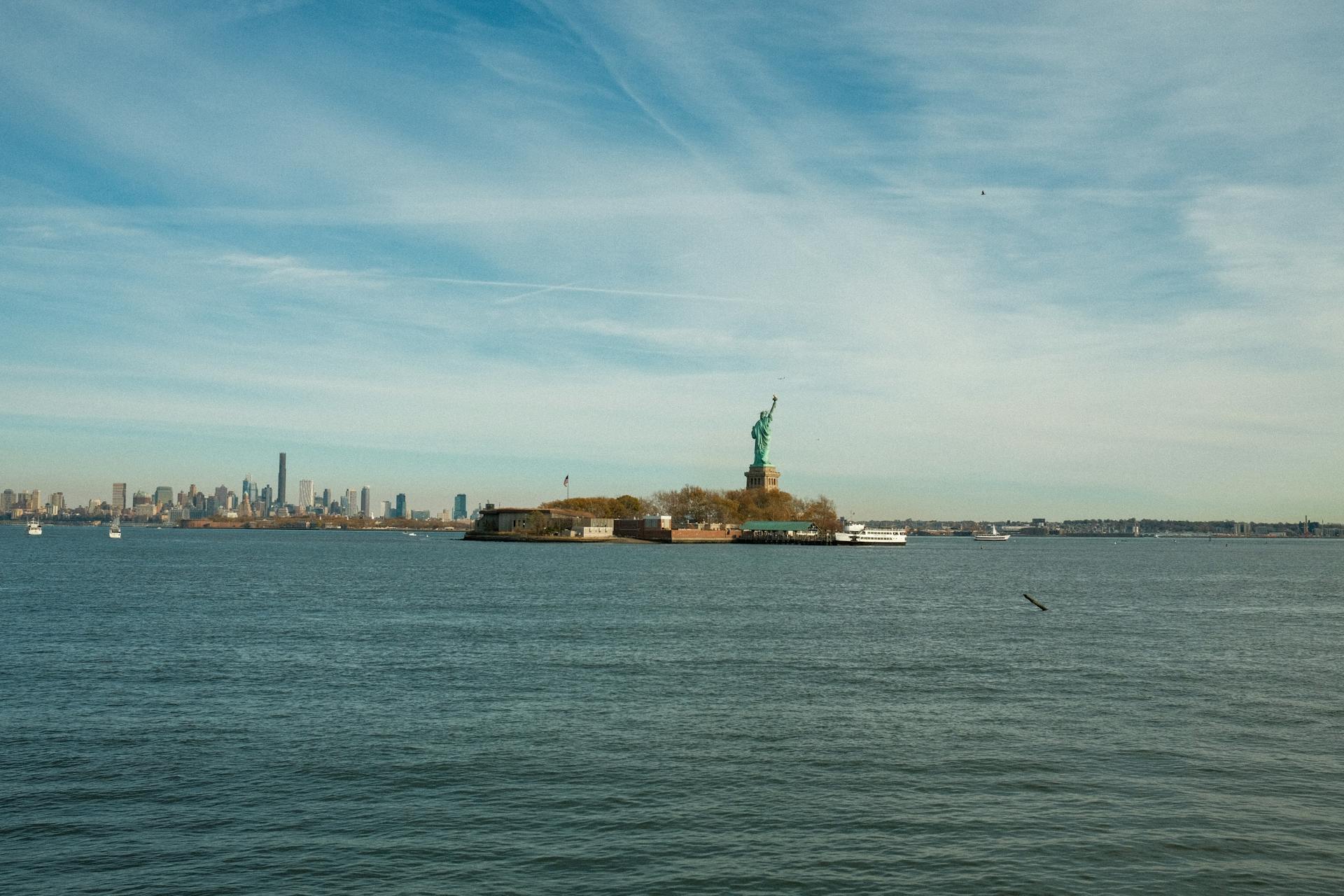 View of the Statue of Liberty with the New York City skyline in the background on a clear day.