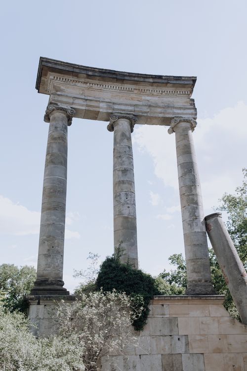 Free Ancient Roman-style columns stand majestically in Sanssouci Park, Potsdam, under a clear sky. Stock Photo