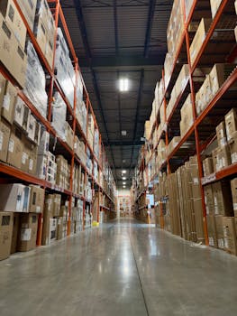 Long aisle in a busy warehouse stacked with boxes and products on shelves.