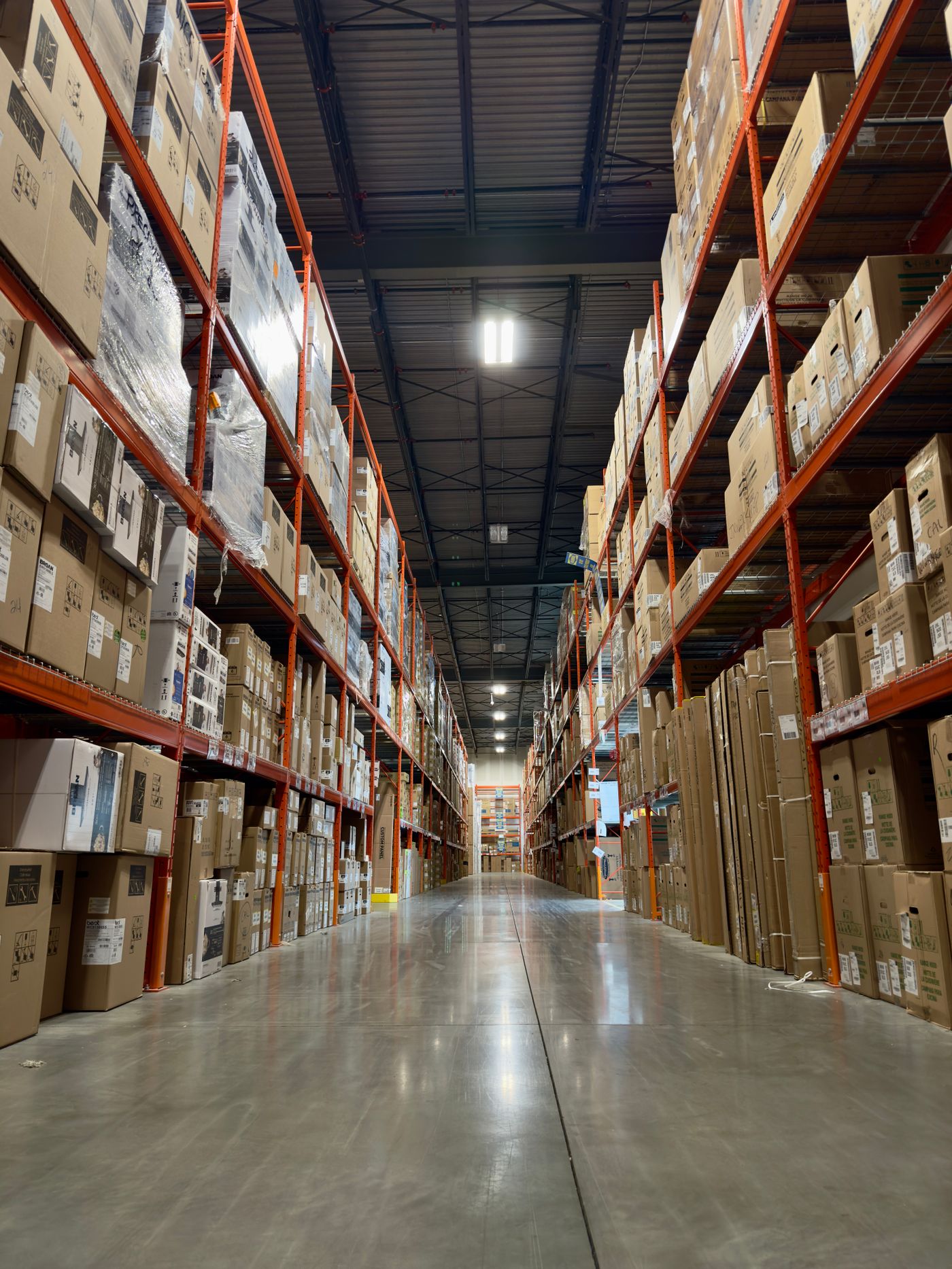 A long warehouse aisle stacked with boxes and products, shown in architectural perspective