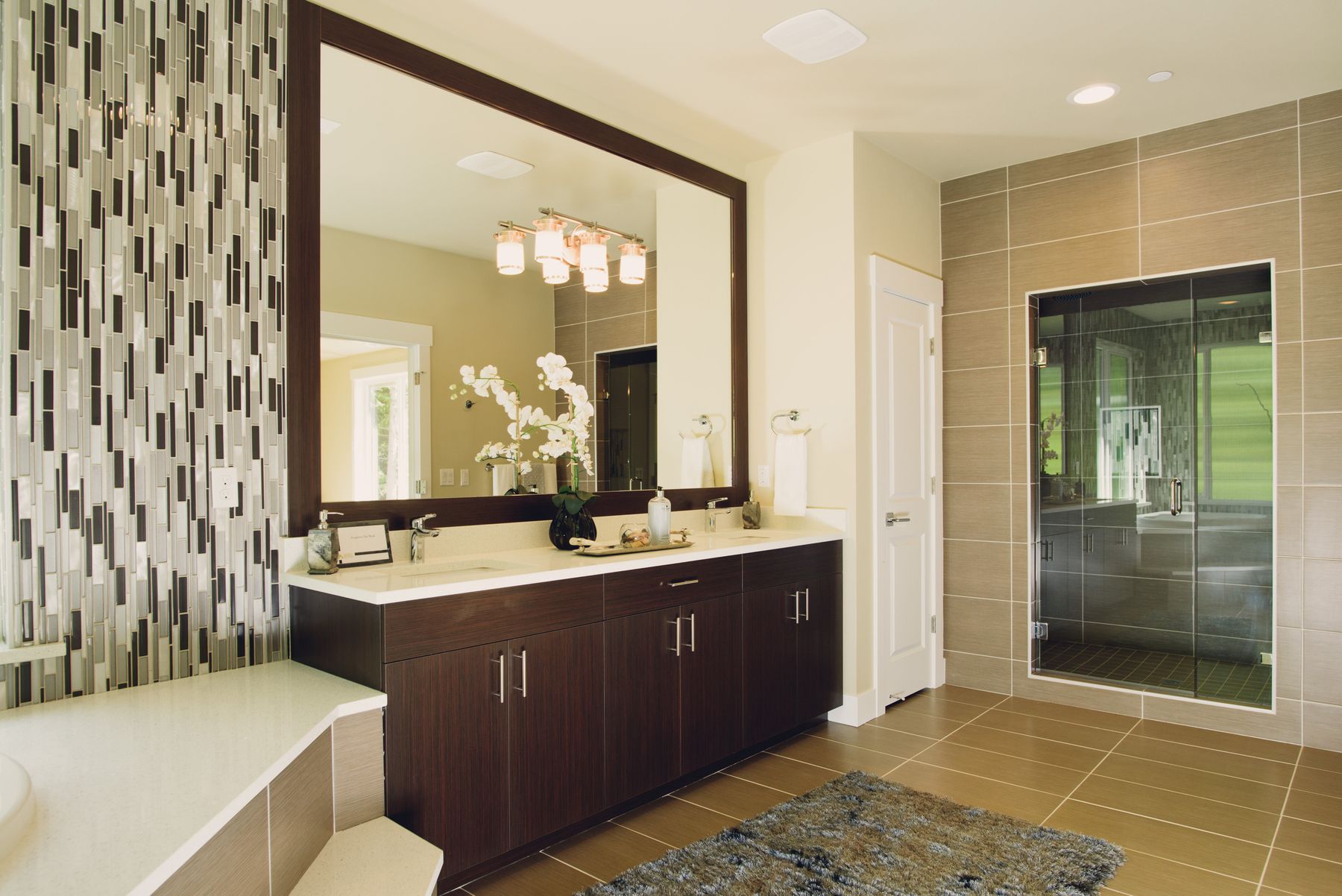 Modern renovated bathroom with vanity, decorative tile, mirror, and glass shower