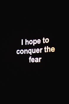 Inspirational neon typography with 'Conquer the Fear' displayed on a dark background.