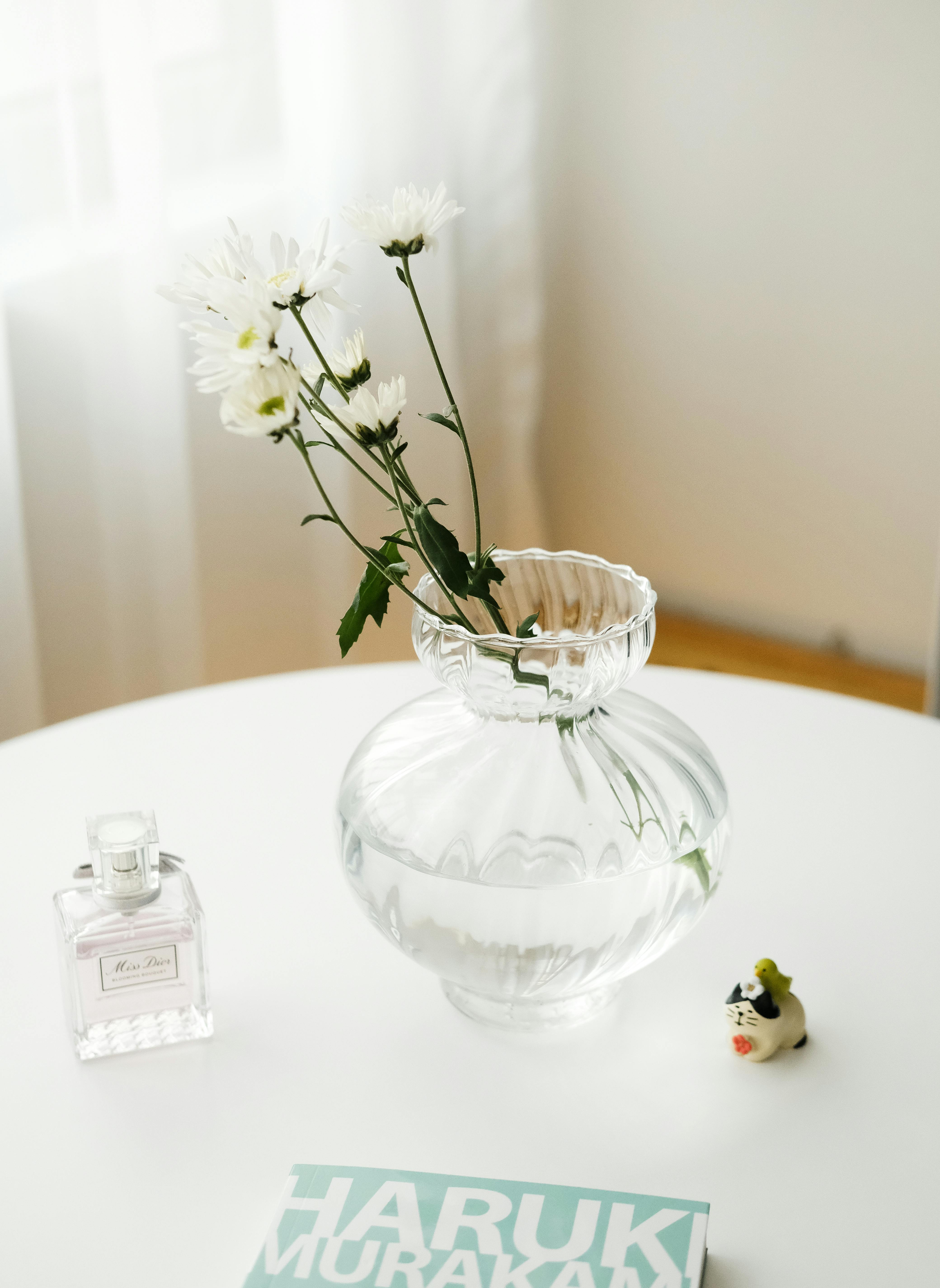 Elegant still life featuring flowers in a vase, perfume, and a book on a table.