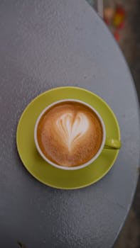 Aerial view of a latte with heart-shaped art in a green cup, on a table outdoors in Istanbul.