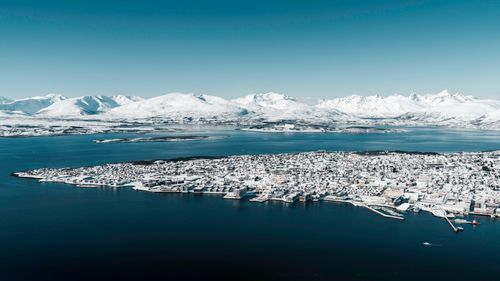 Free Stunning aerial photograph of Tromsø, Norway blanketed in snow with majestic mountains in the background. Stock Photo