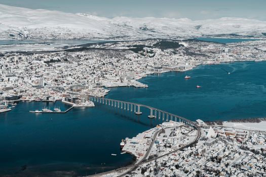 Discover the stunning aerial view of Tromsø in winter, showcasing its iconic bridge and snowy landscape.
