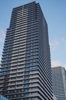 Tall modern high-rise building with glass facades against a clear blue sky.