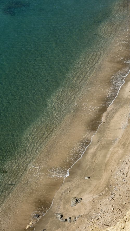 Free Tranquil aerial shot showcasing pristine sandy beach with gentle waves and turquoise waters. Stock Photo