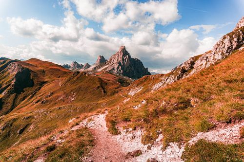 Free Stunning mountain landscape in the Dolomites with a hiking trail under a bright blue sky. Stock Photo