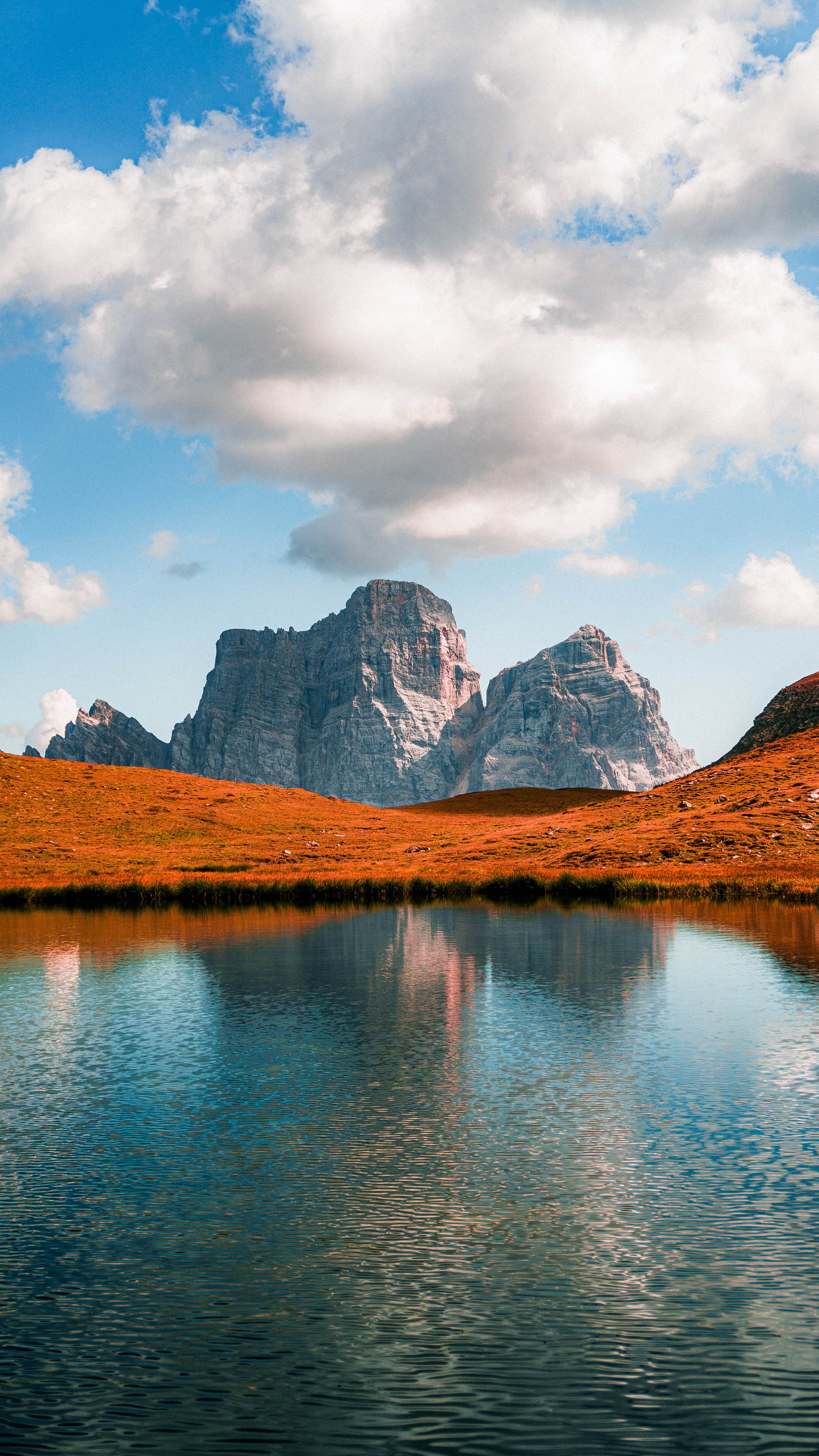 Dynamic view of mountains reflecting in a peaceful lake with vibrant autumn colors.