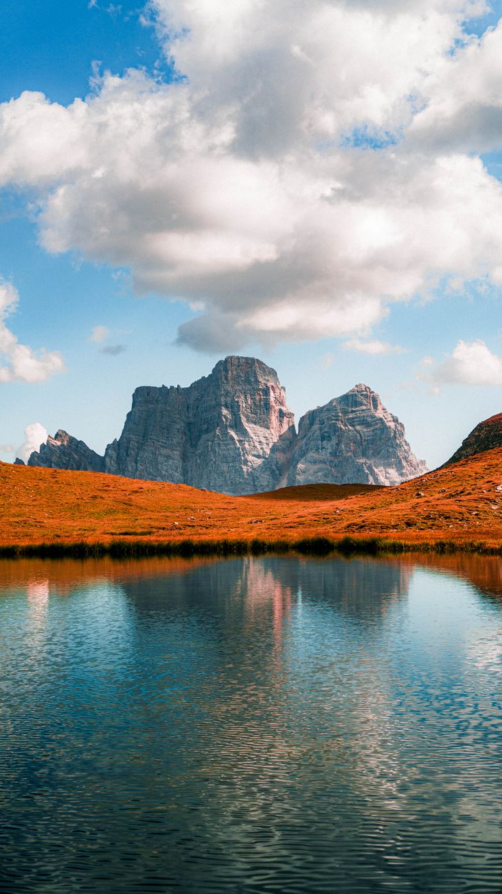 Dynamic view of mountains reflecting in a peaceful lake with vibrant autumn colors.