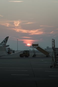 Captivating sunset over Schwechat Airport tarmac with an airplane wing and boarding stairs in view.
