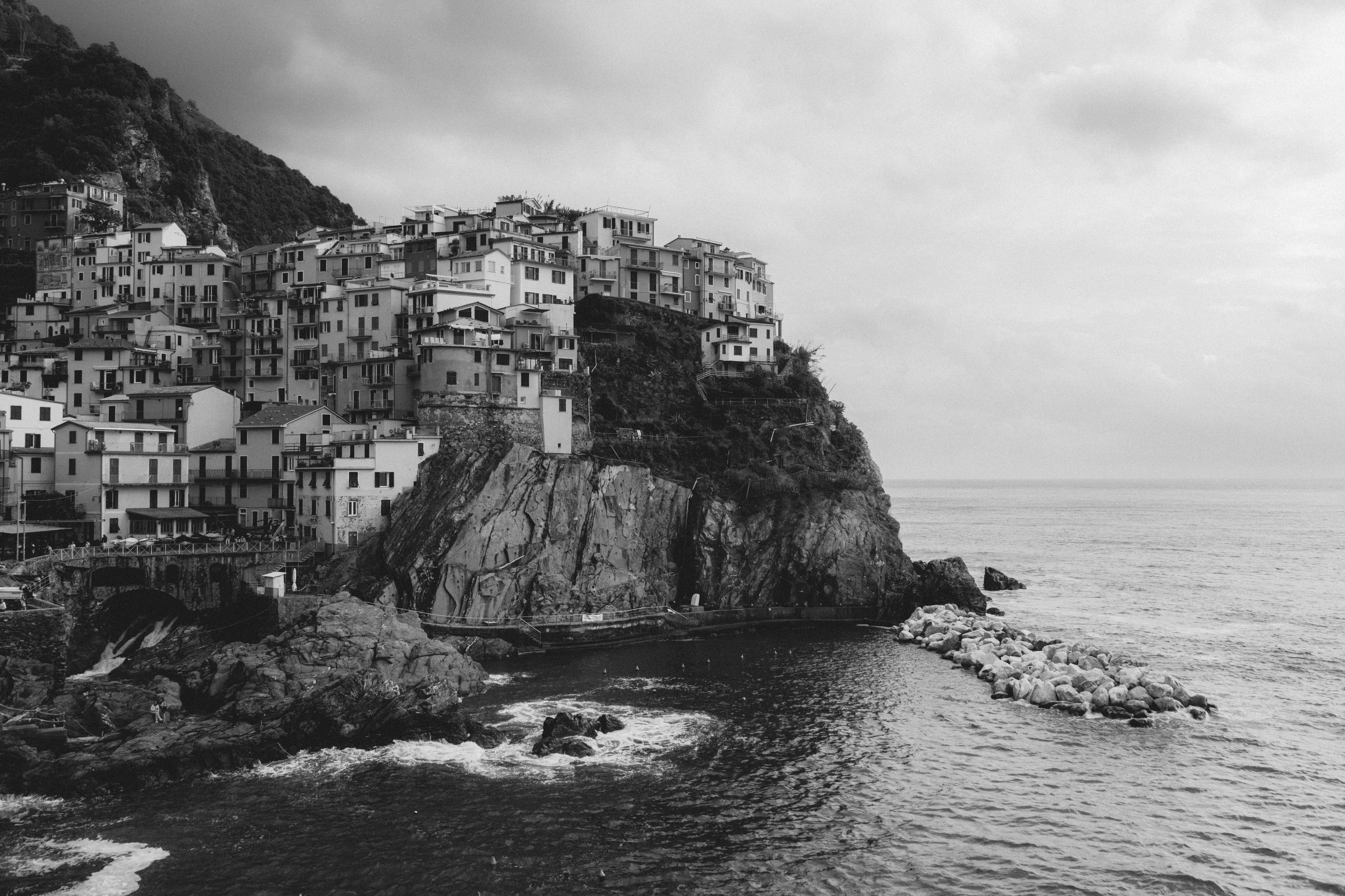 Black and white photo of a coastal town on a rocky cliff in Manarola, Italy.