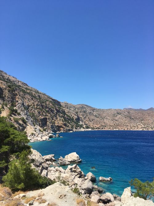 Free Vibrant blue Aegean sea meets rocky cliffs under a clear sky, embodying natural beauty. Stock Photo