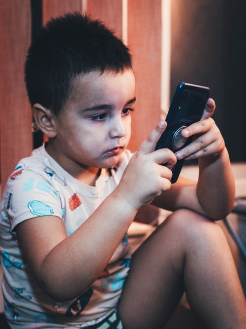Free Child intensely focused on a smartphone indoors, showcasing modern technology impact. Stock Photo