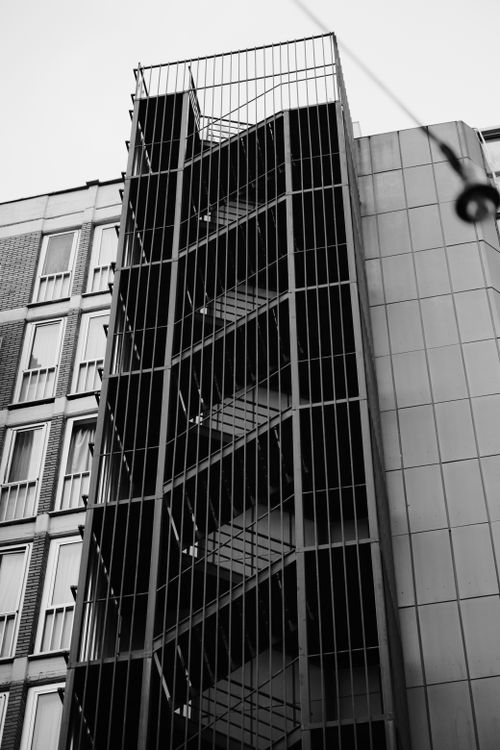 Free Black and white photo of an exterior fire escape on a city building. Stock Photo