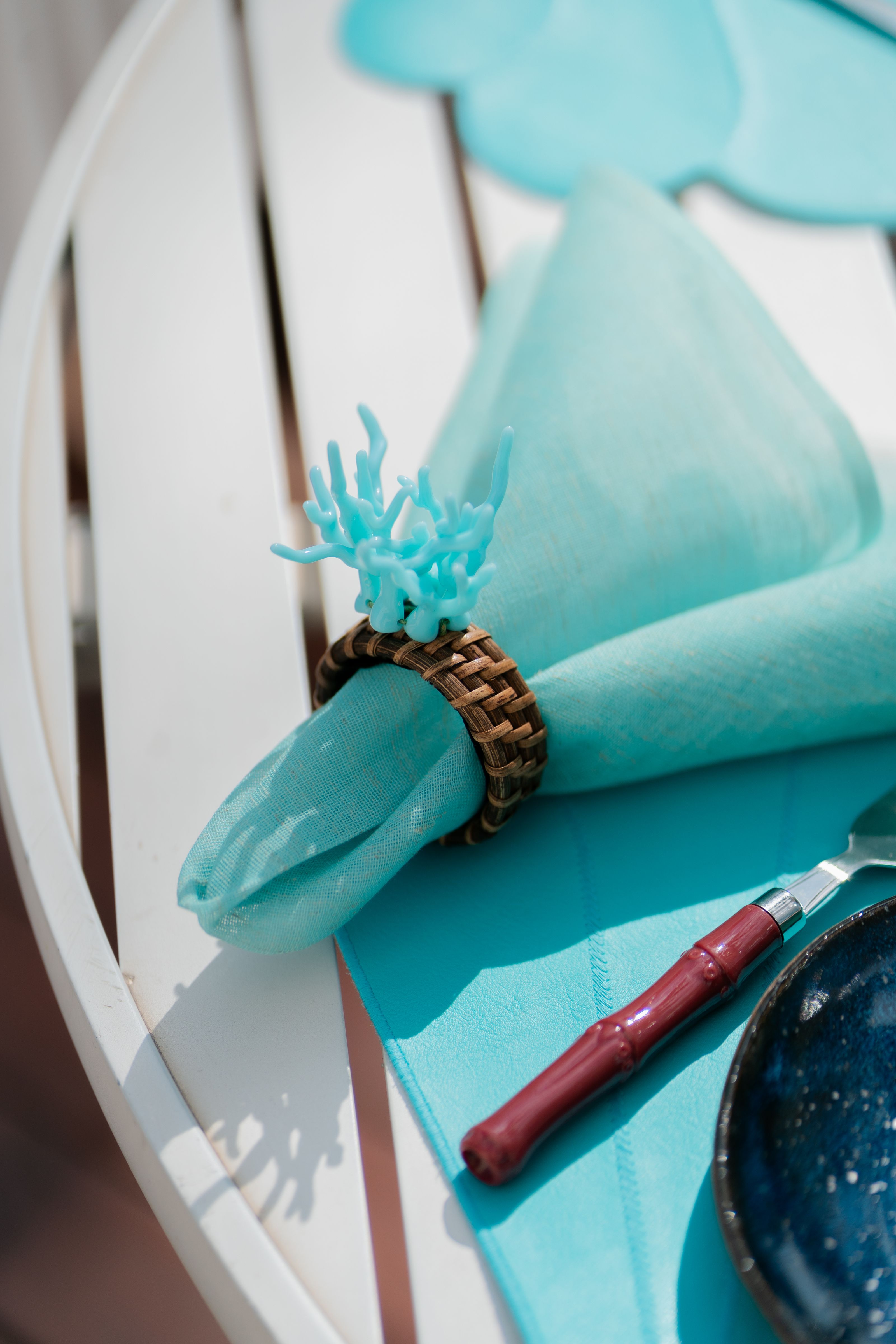 Elegante arranjo de mesa turquesa com porta-guardanapos com tema coral e talheres artísticos.