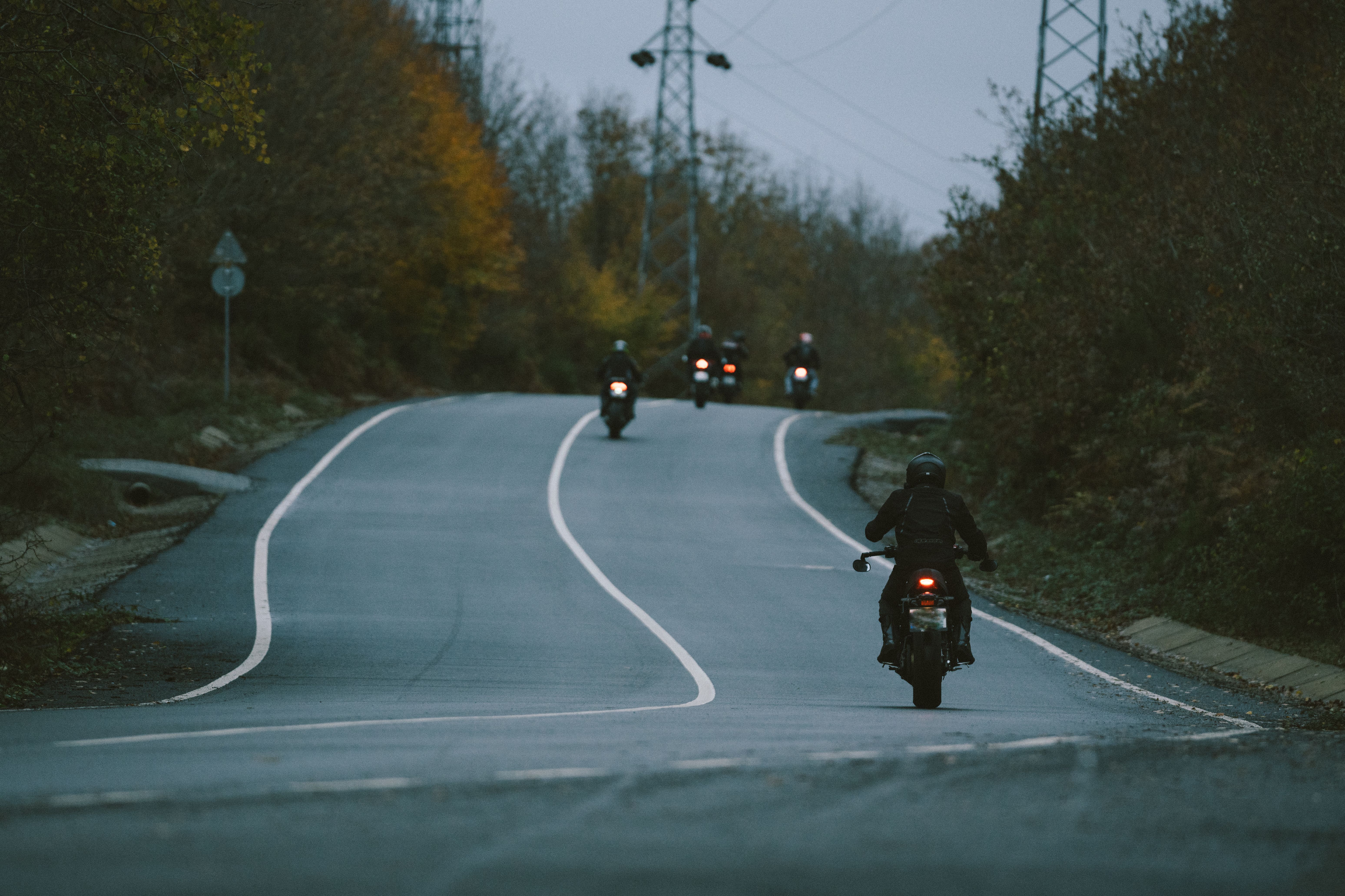Grupo de motociclistas em estrada sinuosa ao entardecer
