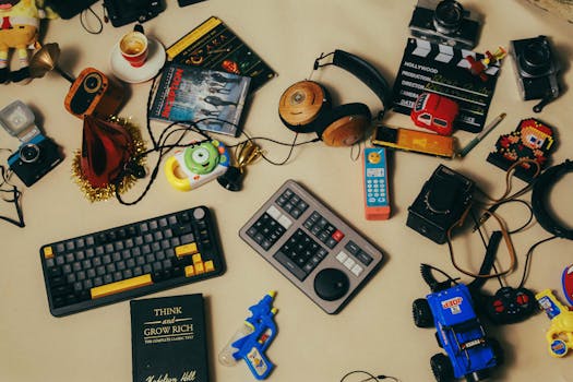 Flat lay of a cluttered creative workspace with gadgets, toys, and film editing tools.