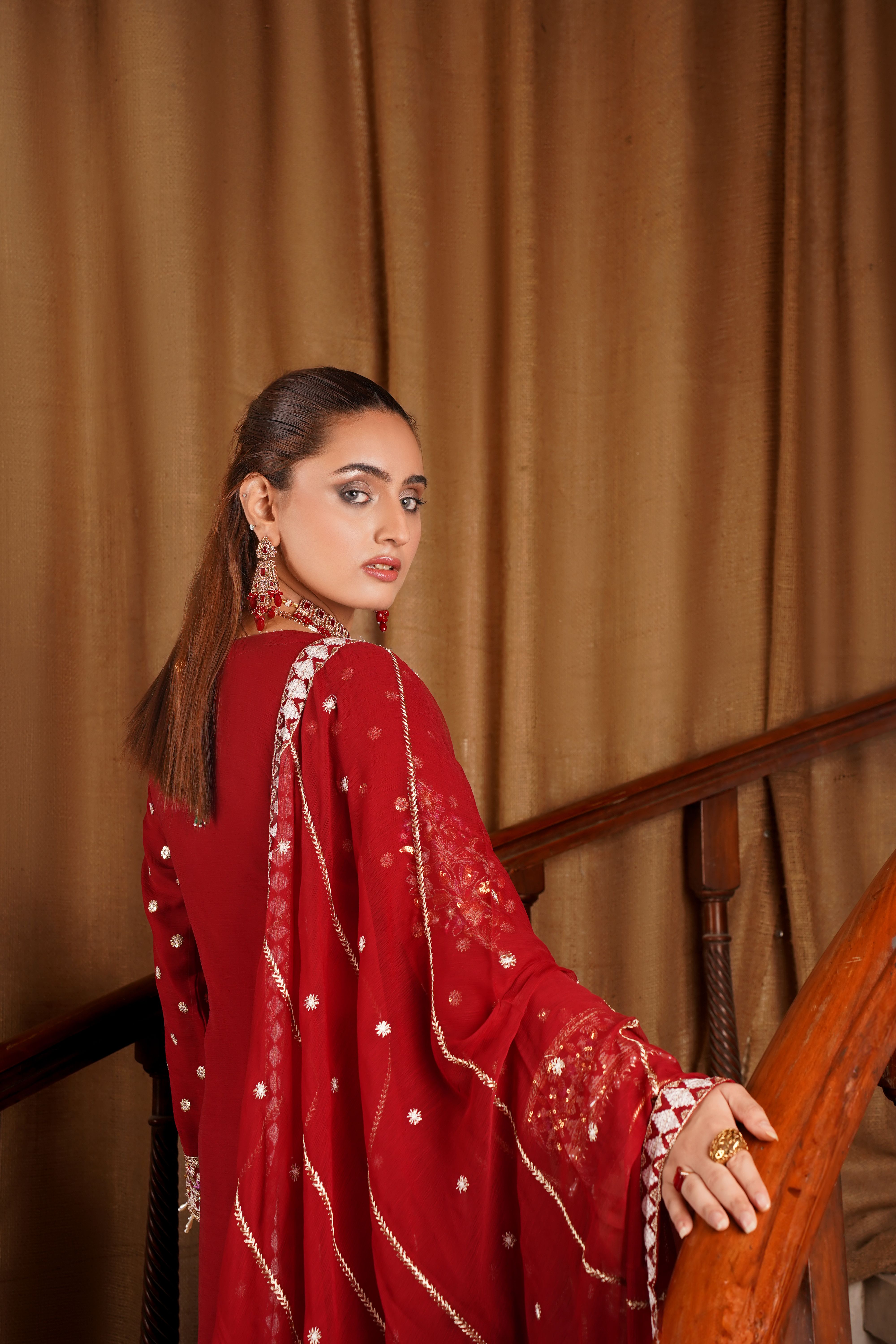 Portrait of a woman in Lahore wearing red traditional attire, exuding elegance.