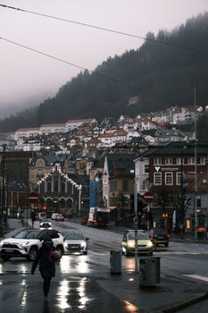 Street view of Bergen, Norway on a rainy evening with cars and pedestrians.
