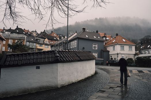 Charming misty street scene with colorful houses in Bergen, Norway.