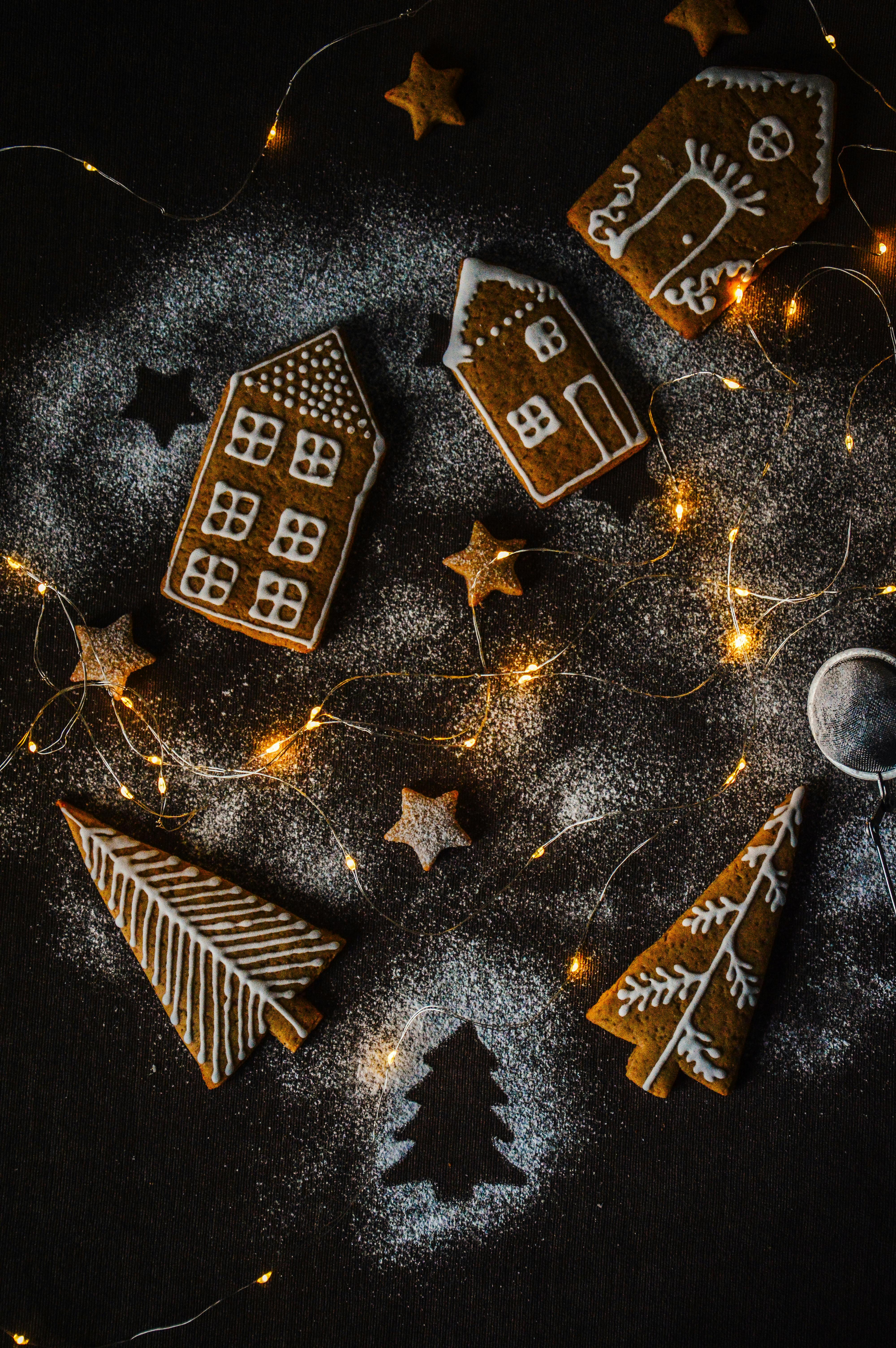 Gingerbread cookies with icing on a dark background with holiday lights.