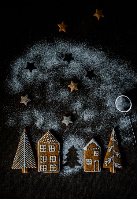 Creative arrangement of gingerbread cookies and powdered sugar stars on dark background.