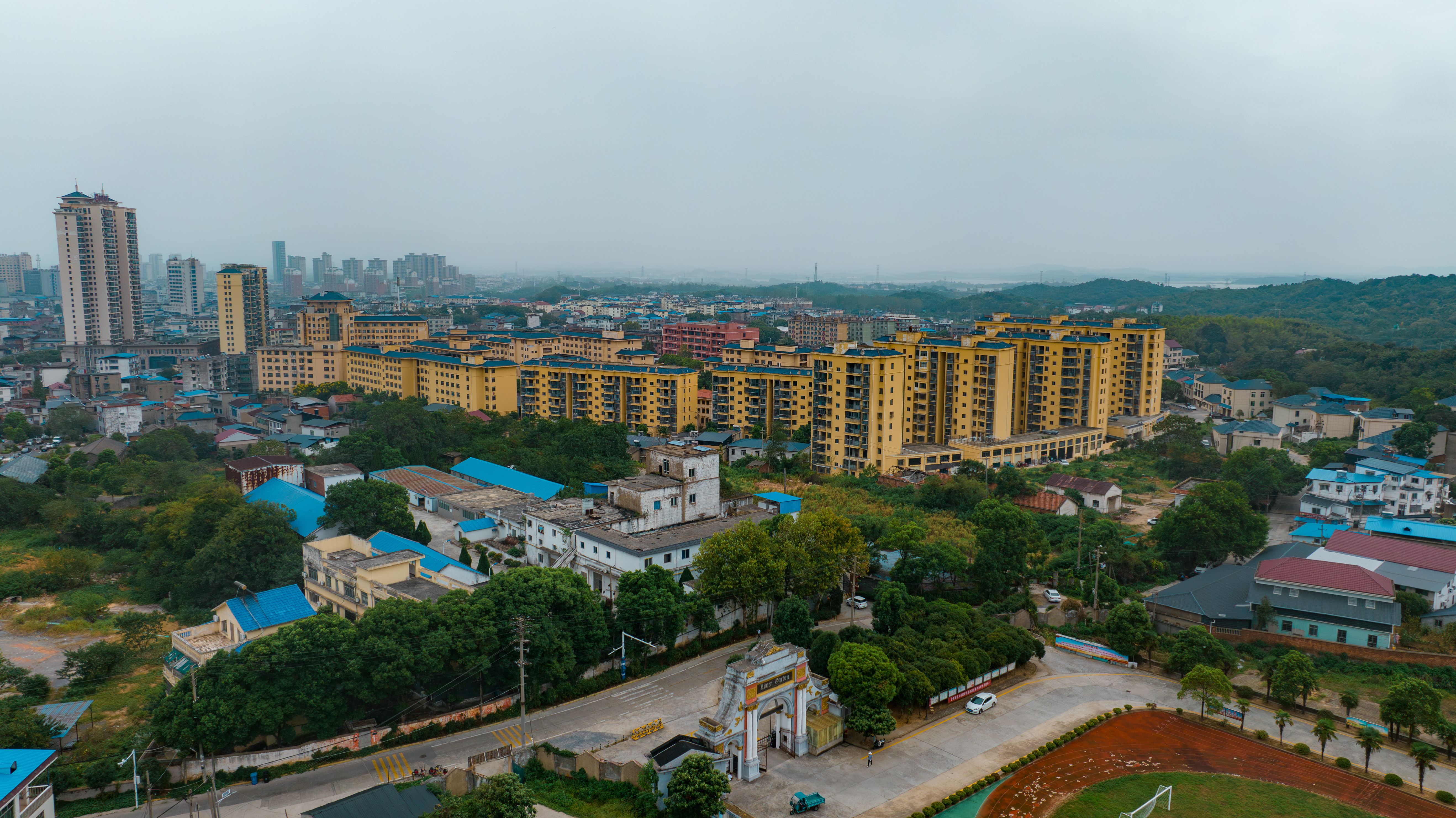 Aerial cityscape of Huanggang, China showcasing residential buildings and greenery.