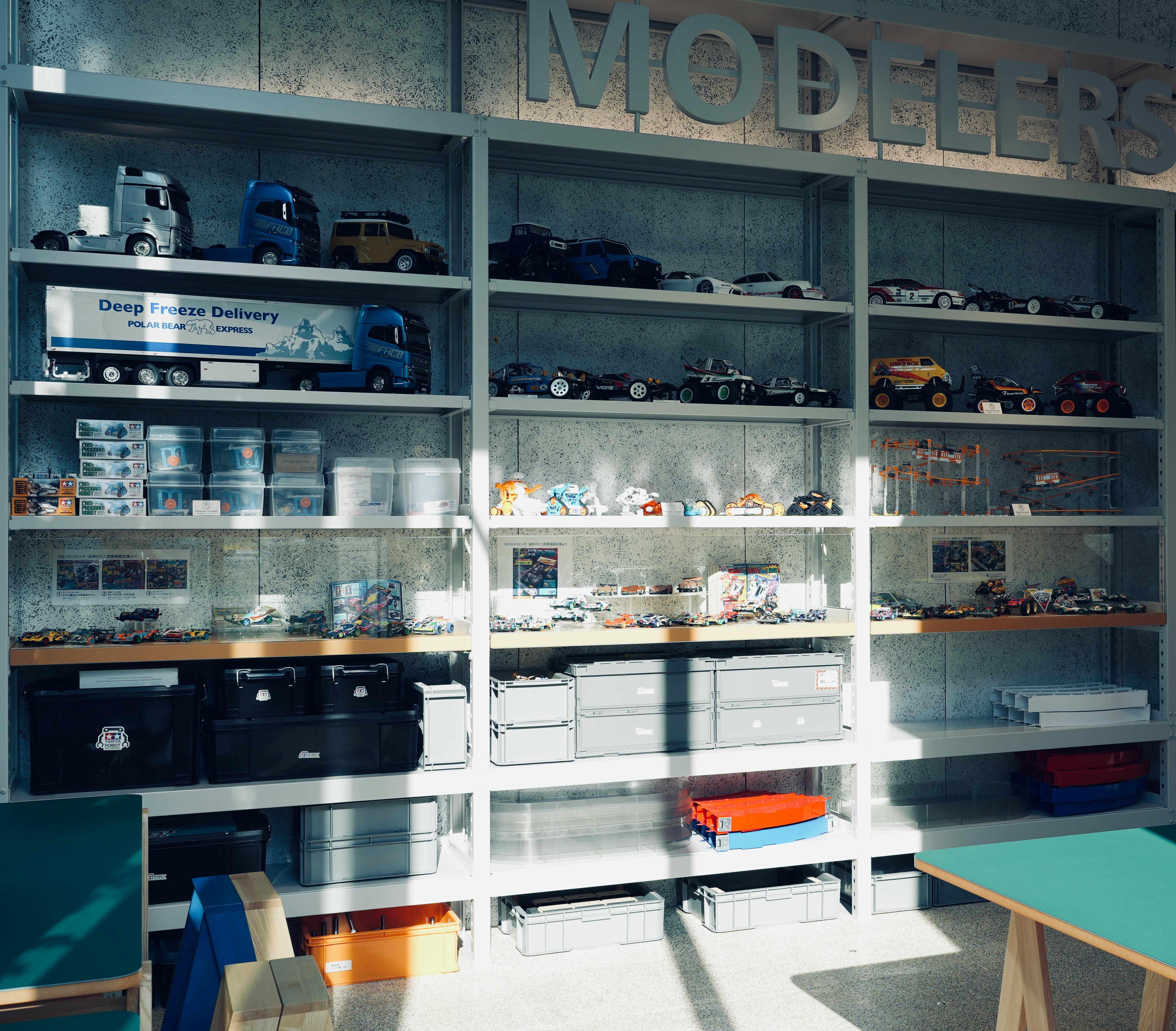 Ücretsiz İyi aydınlatılmış bir odada metal raflarda düzenlenmiş model arabalar ve saklama kapları koleksiyonu. Stok Fotoğraflar