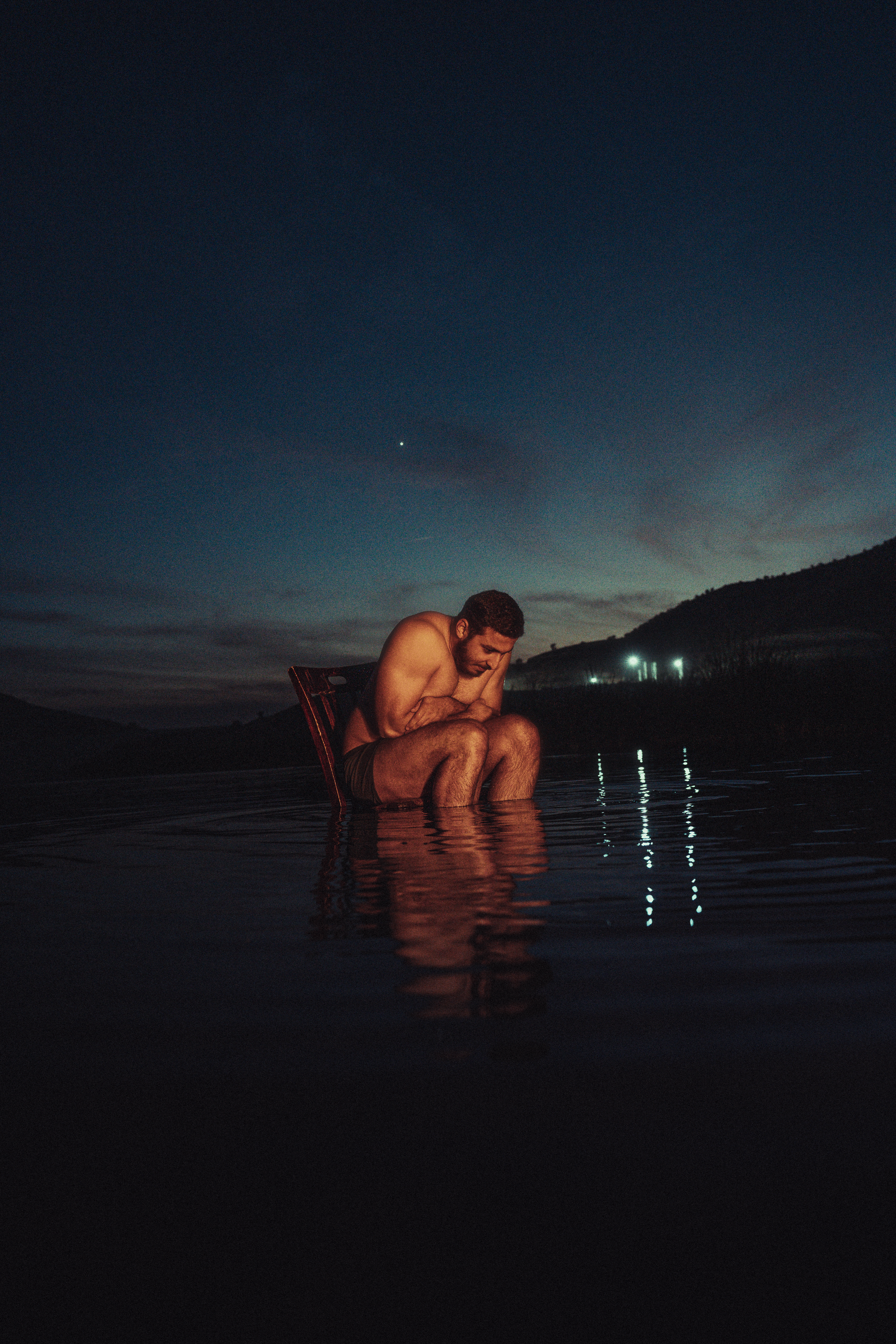 Contemplative Man Sitting in Water at Dusk · Free Stock Photo