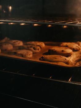 Warm chocolate chip cookies baking inside an oven, emitting a cozy aroma.