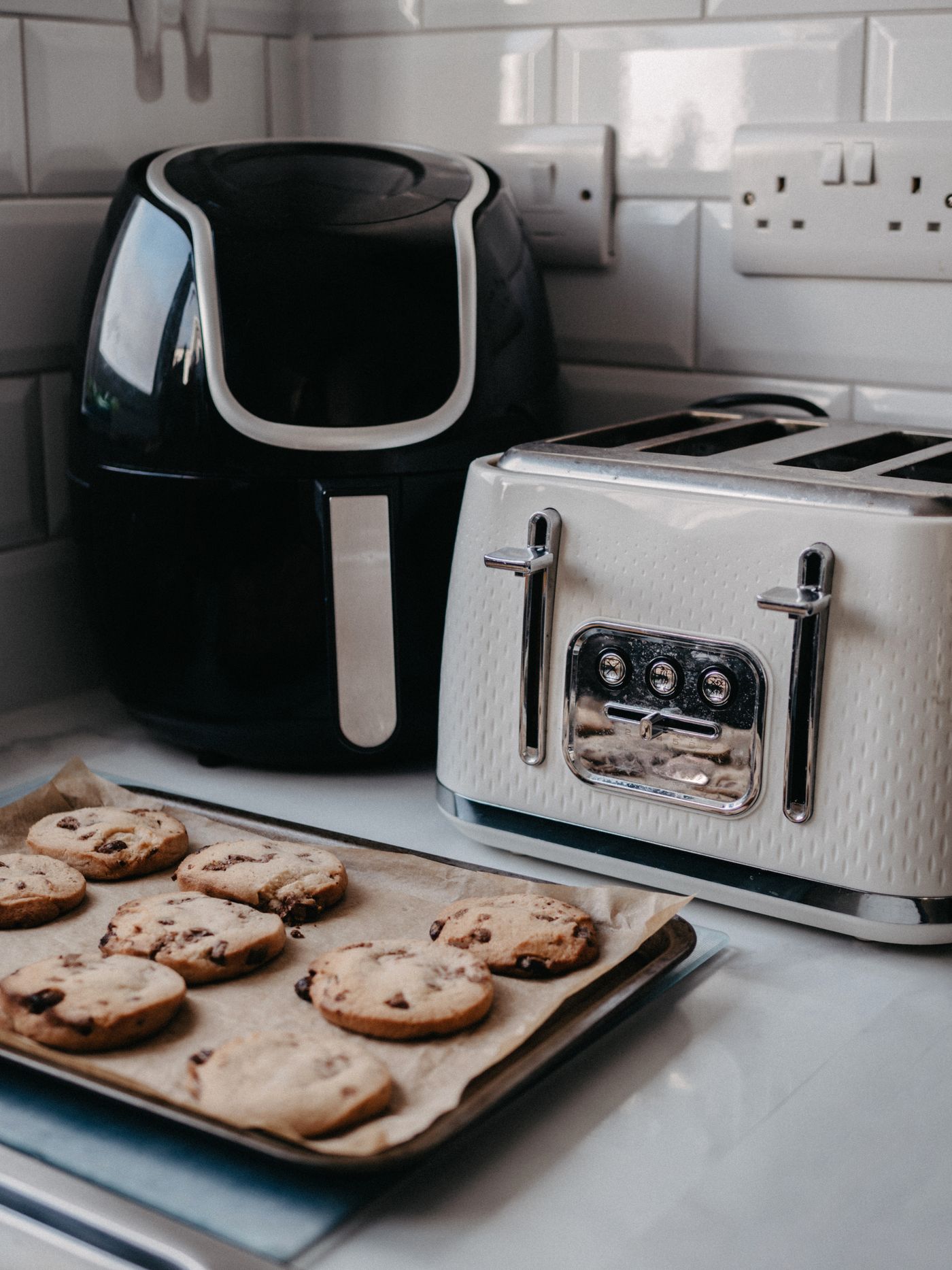 Air fryer and toaster arranged in a modern kitchen beside freshly prepared baked food