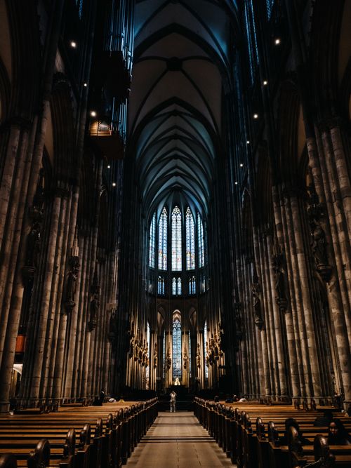 Free Dramatic view of a Gothic cathedral's interior featuring stained glass windows and soaring arches. Stock Photo