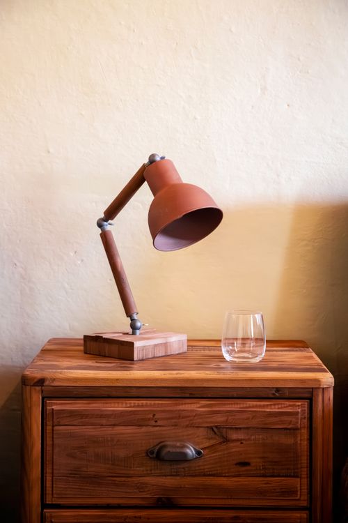 Free A rustic wooden table featuring an industrial lamp and an empty glass, casting a warm ambiance. Stock Photo