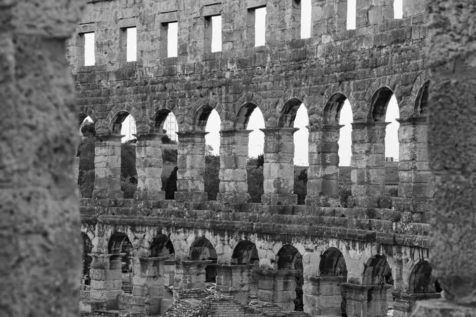 Black and white photo of a historic Roman amphitheater showcasing intricate stone arches.