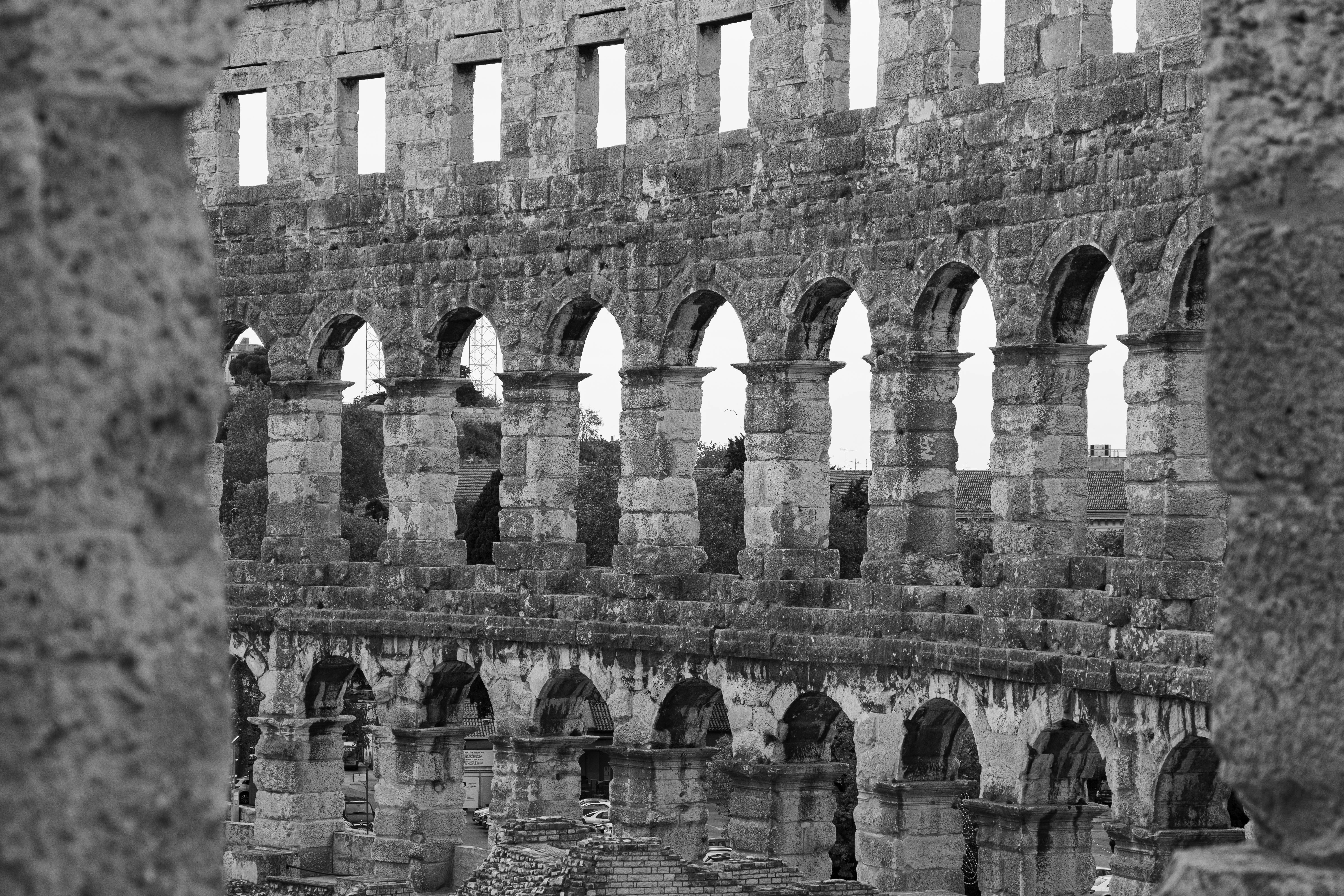 Free Black and white photo of a historic Roman amphitheater showcasing intricate stone arches. Stock Photo