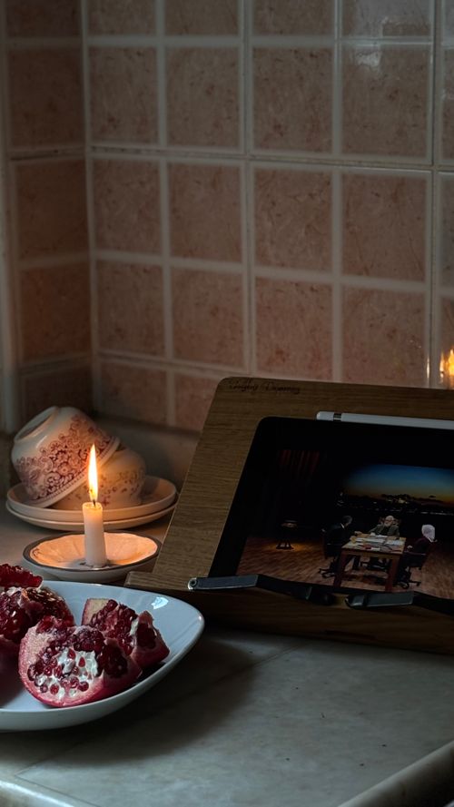 Free A candlelit kitchen scene with sliced pomegranate and a digital photo frame for a warm, homely vibe. Stock Photo