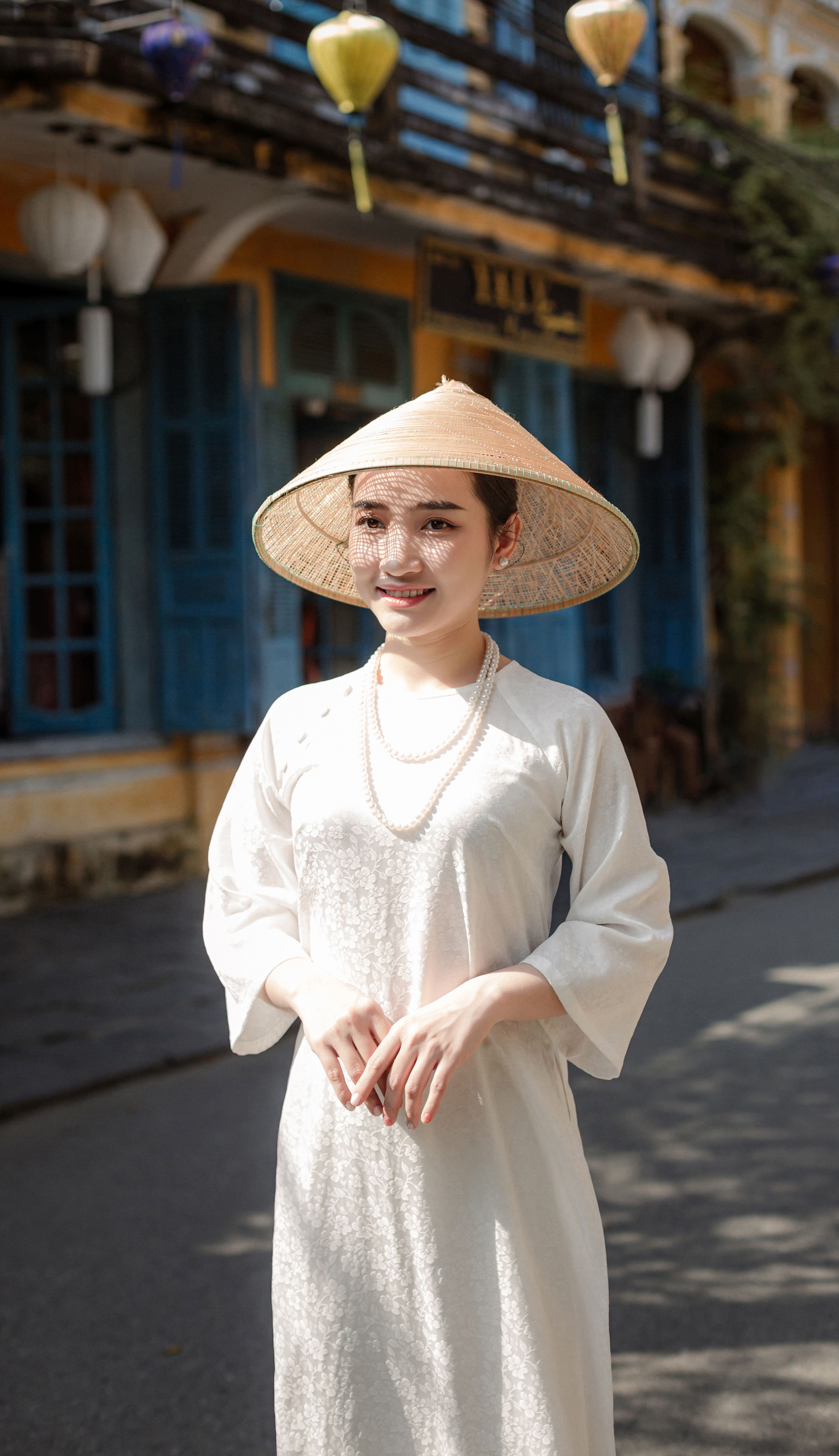 Woman in traditional Vietnamese attire on a sunlit street in Hội An.