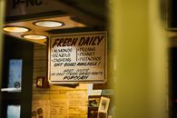 Indoor sign showcasing fresh nuts and dried fruits selection available daily in a cozy store setting.