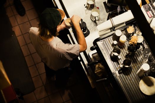 Barista preparing coffee, captured from above, highlighting cafe ambiance and artisanal skills.