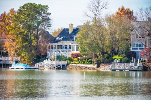 Picturesque lakeside home surrounded by vibrant autumn foliage. Ideal for real estate or travel themes.