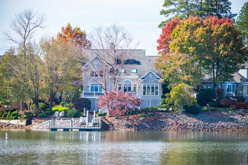 Free Charming house by the lake surrounded by vibrant autumn trees reflecting on water. Stock Photo