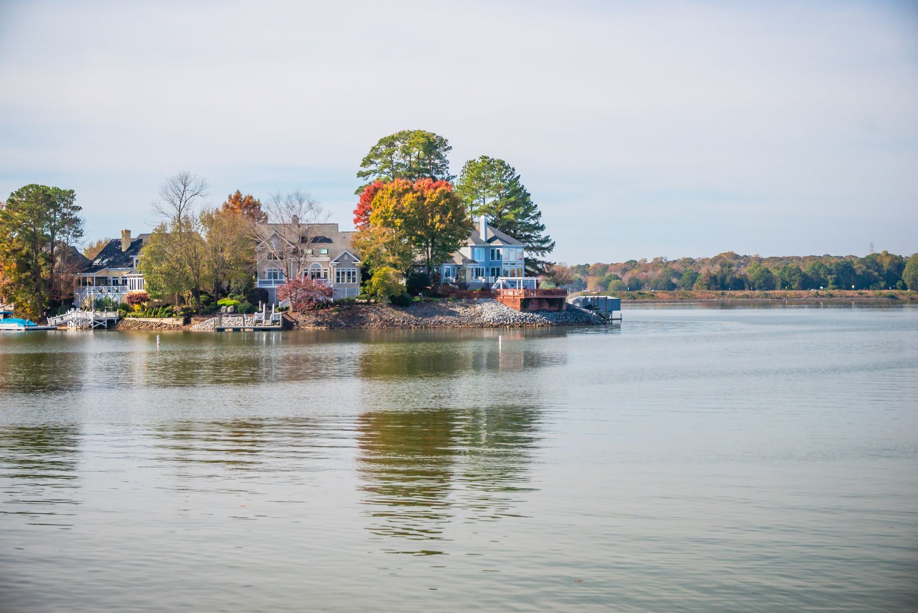 Beautiful lakeside houses surrounded by autumn trees and calm water reflecting the serene setting.