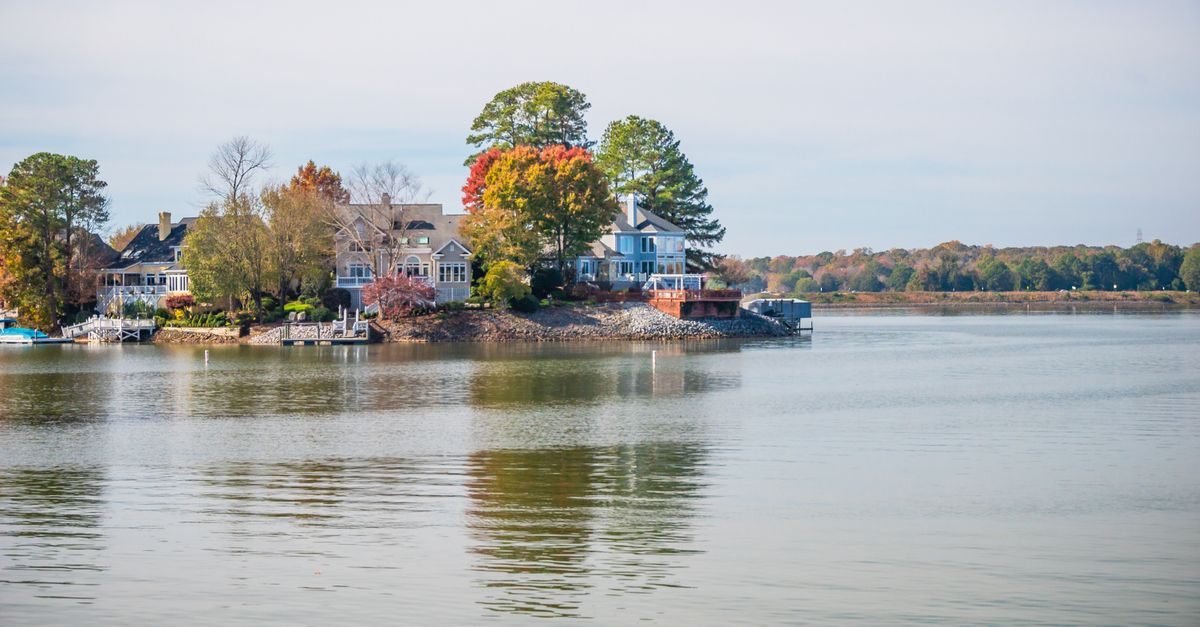 Beautiful lakeside houses surrounded by autumn trees and calm water reflecting the serene setting.