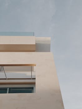 A minimalist building exterior showcasing clean lines and warm tones against a blue sky.