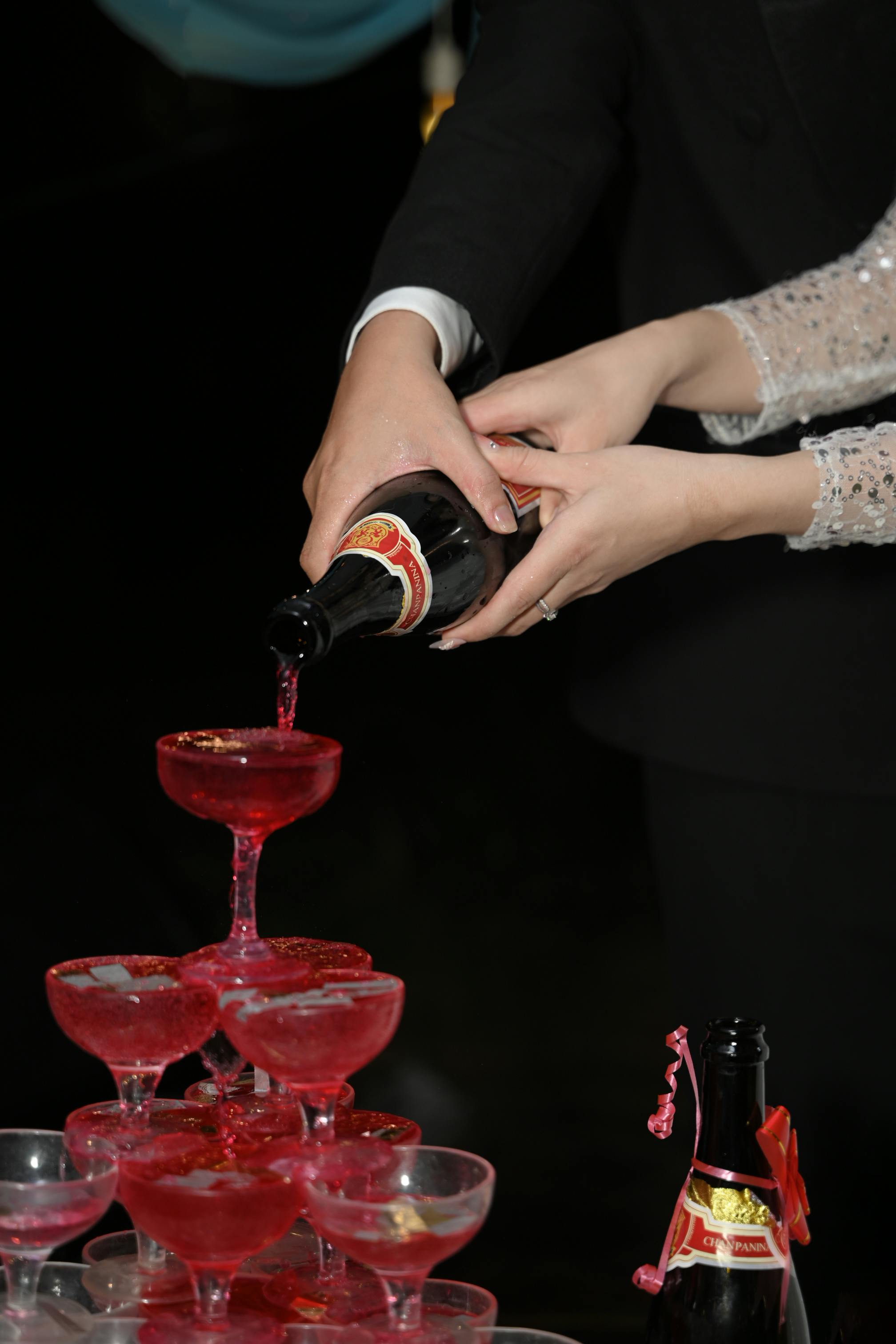Bride pouring pink cocktail in the glass towers