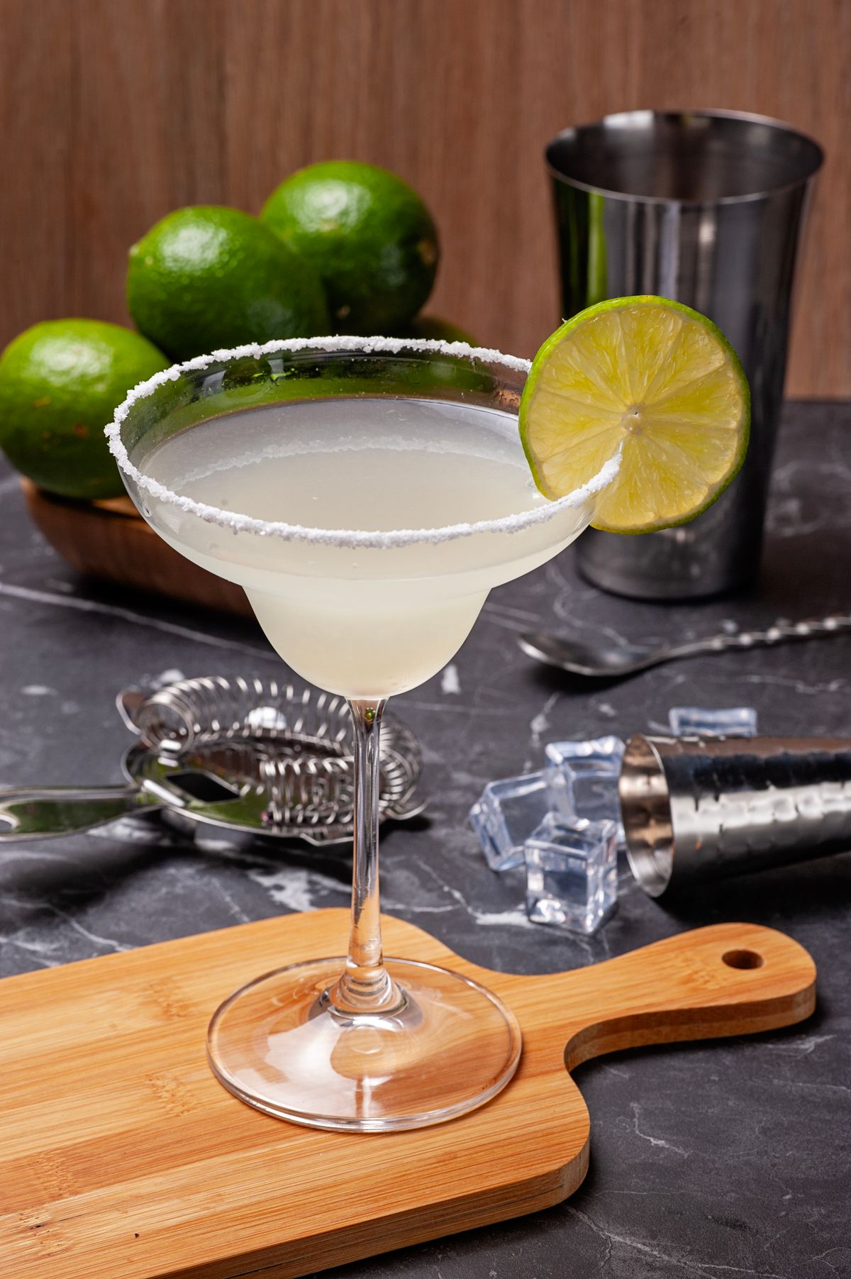 Margarita classique givrée au sel, garnie d'une rondelle de citron vert, servie sur une planche en bois
