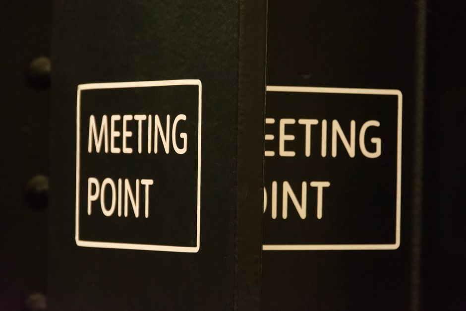 Close-up view of a 'Meeting Point' sign in an urban setting, conveying location and coordination.