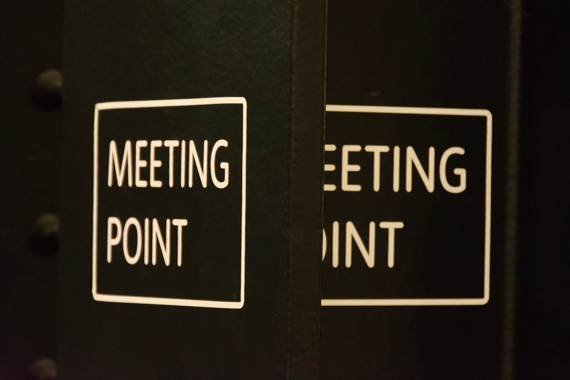 Close-up view of a 'Meeting Point' sign in an urban setting, conveying location and coordination.